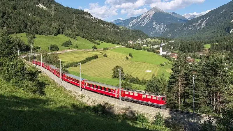 Red train crossing a mountain landscape